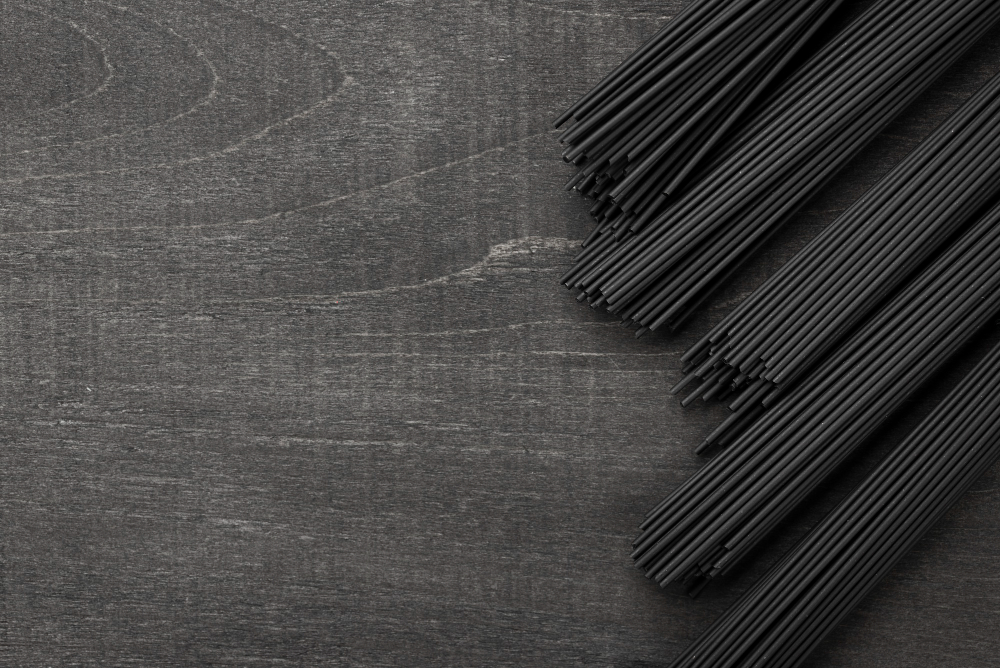 A collection of black straws sticks elegantly arranged on a wooden table, representing stylish and sustainable straws.