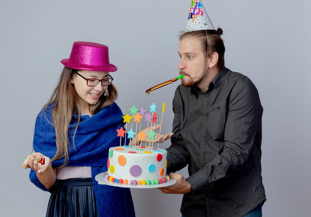 A man and woman share a moment of joy as they blow out candles on a birthday cake, marking a special celebration together.