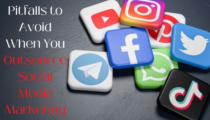 A dark gray table scattered with 3D social media icons (YouTube, Instagram, Facebook, Twitter, Telegram, WhatsApp, TikTok), with the overlaid text “Pitfalls to Avoid When You Outsource Social Media Marketing.